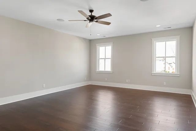 an empty room with windows and fan