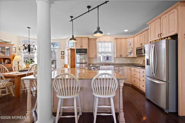 a kitchen with stainless steel appliances granite countertop a stove a sink dishwasher and wooden cabinets with wooden floor