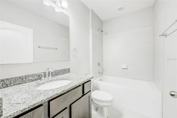 a bathroom with a granite countertop sink a toilet and shower