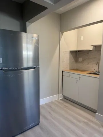 a view of a refrigerator in kitchen and an empty room