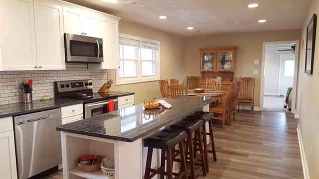 5115 Bethlehem Road Boones Mill, VA 24065 - Photo 9 of 42 a kitchen with stainless steel appliances granite countertop a stove top oven a sink a dining table and chairs with wooden floor