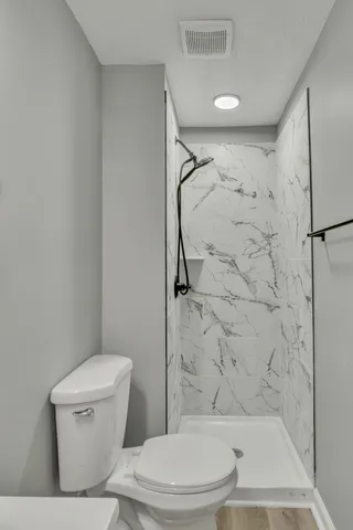 a white toilet sitting next to a bath tub and a shower