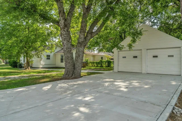 a view of a house with a yard and large trees