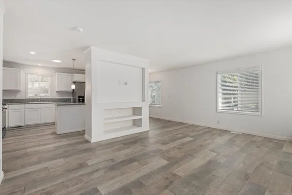 an empty room with wooden floor and windows
