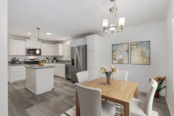 a kitchen with a refrigerator a stove a sink a dining table and chairs