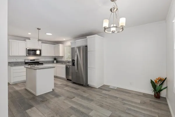 a kitchen with a refrigerator a sink dishwasher a stove and white cabinets with wooden floor