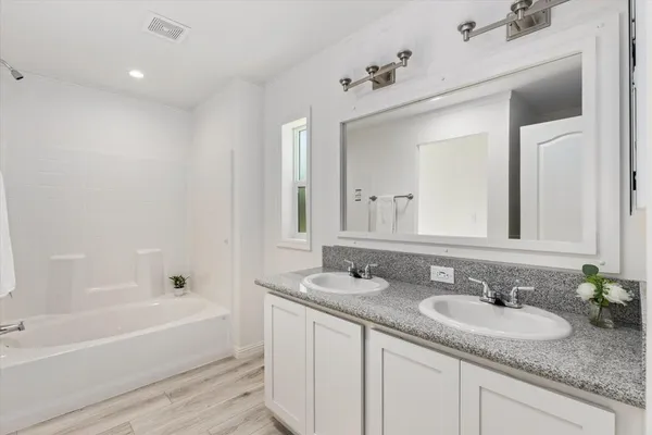 a bathroom with a granite countertop tub sink and mirror