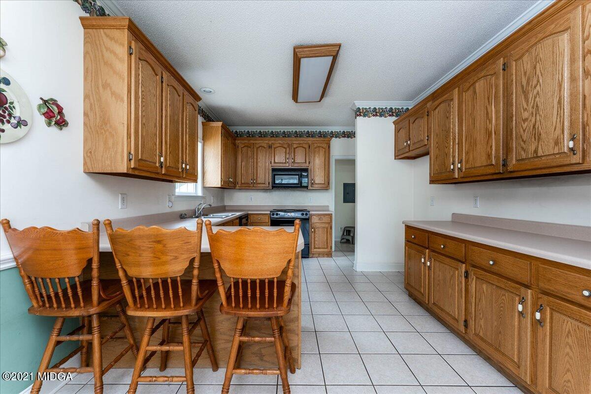 7455 Columbus Road Lizella, GA 31052 - Photo 13 of 32 a kitchen with stainless steel appliances granite countertop a table chairs and a wooden cabinets
