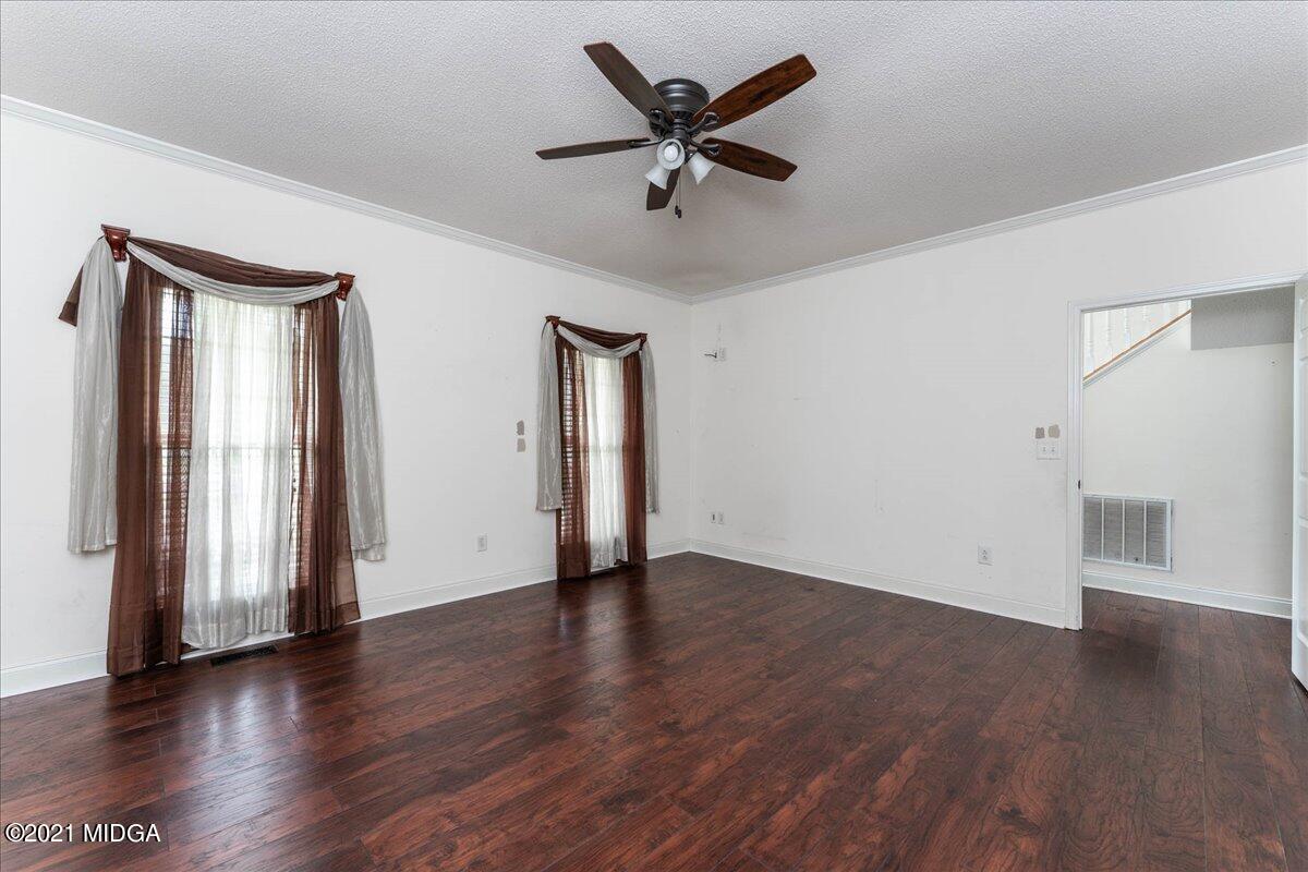 7455 Columbus Road Lizella, GA 31052 - Photo 20 of 32 an empty room with wooden floor a ceiling fan and windows