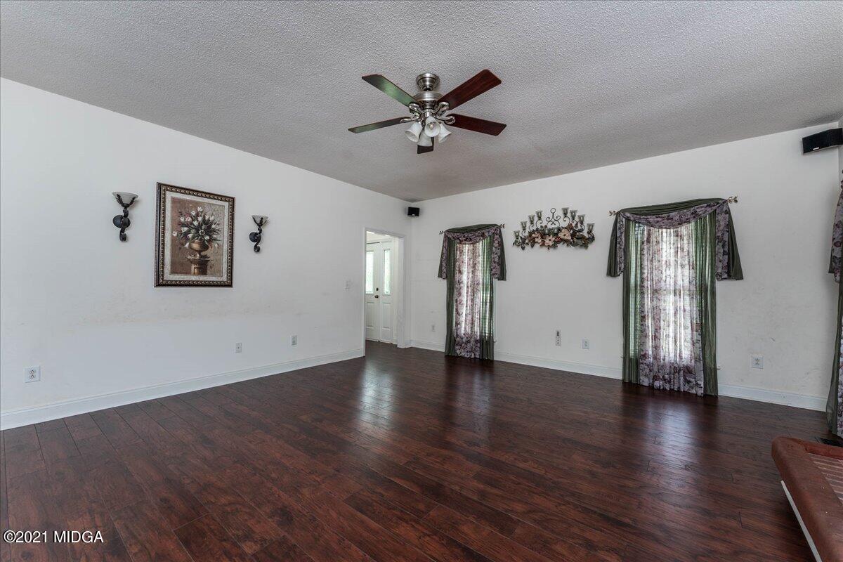 7455 Columbus Road Lizella, GA 31052 - Photo 26 of 32 an empty room with wooden floor a ceiling fan and windows