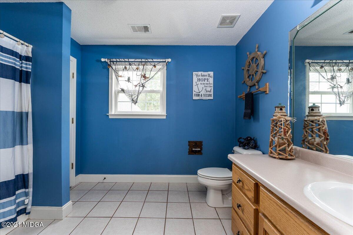 7455 Columbus Road Lizella, GA 31052 - Photo 30 of 32 a bathroom with a sink a toilet and shower curtain