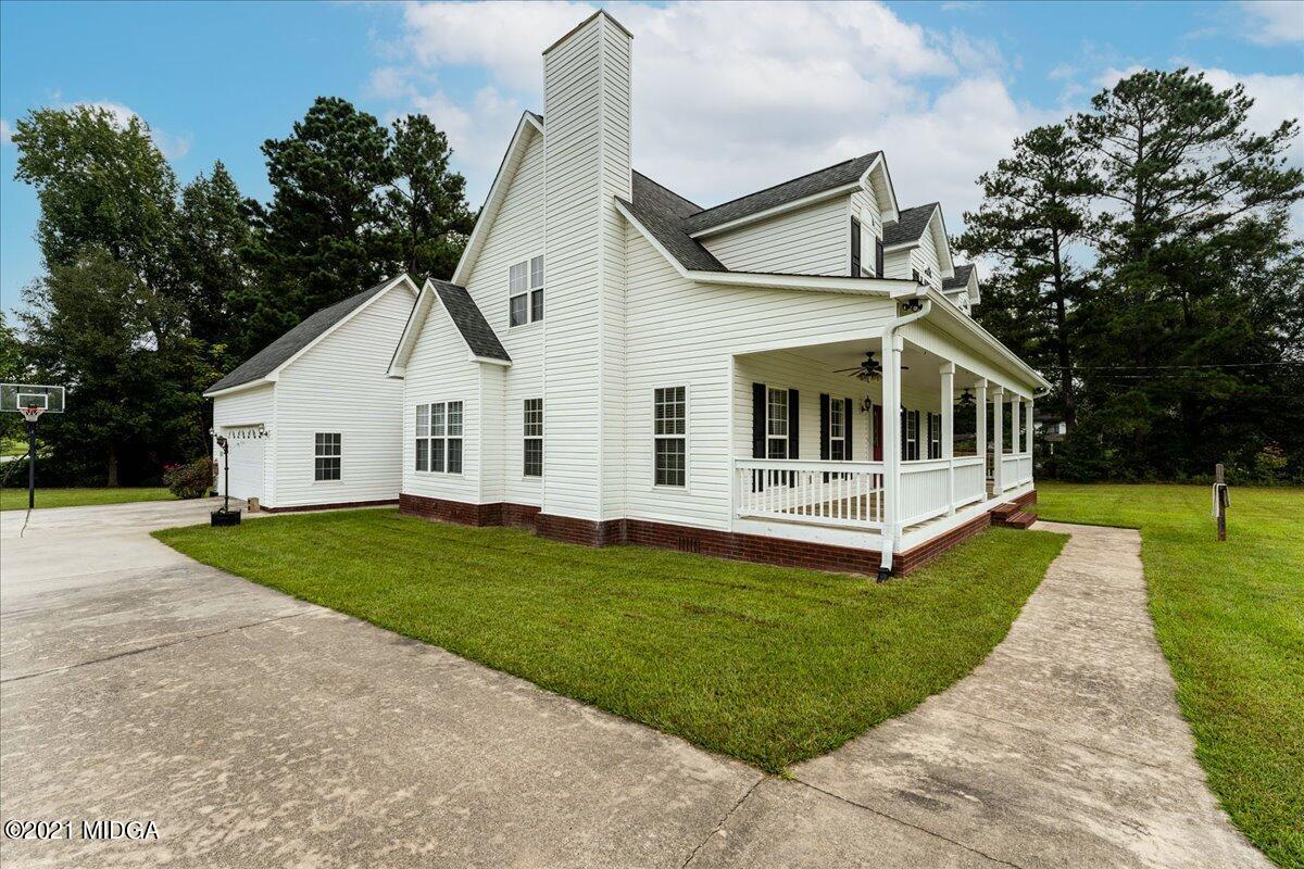 7455 Columbus Road Lizella, GA 31052 - Photo 7 of 32 a view of a white house with a big yard and potted plants