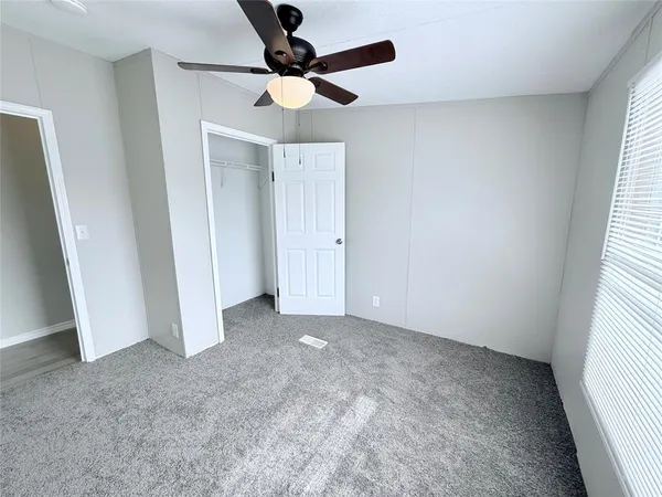 an empty room with a window and a fan