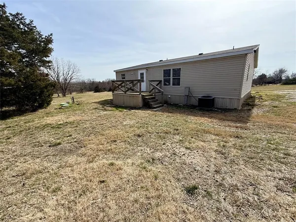 a backyard of a house with wooden fence and a lawn chairs