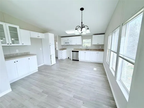 a large kitchen with cabinets wooden floor and stainless steel appliances