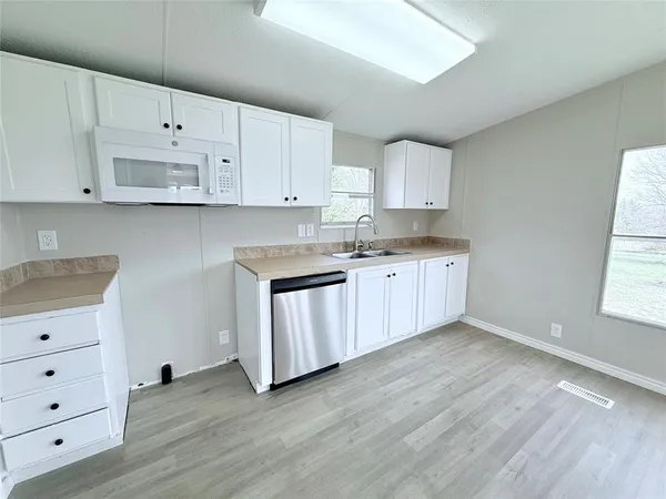 a kitchen with cabinets wooden floor and black appliances