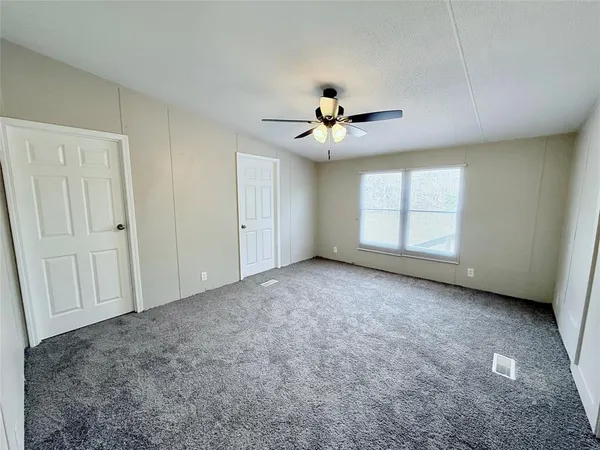 an empty room with windows and ceiling fan