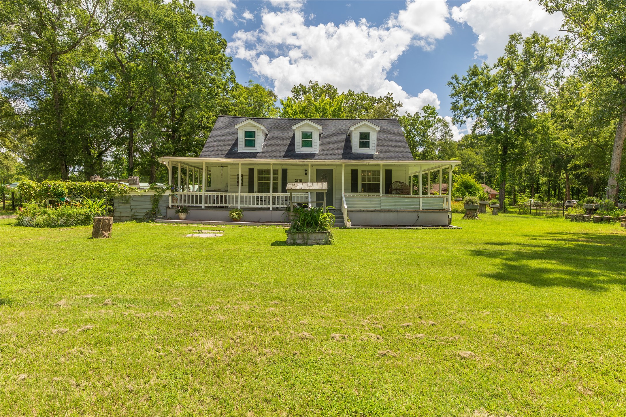 2118 Rolling Hills Road Conroe, TX 77303 - Photo 1 of 39 Classic farmhouse style exterior features a welcoming wraparound porch overlooking the peaceful property.