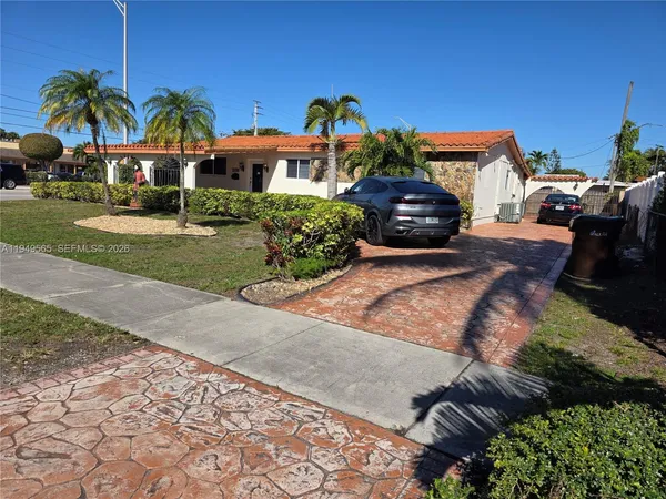 a front view of a house with a yard and potted plants