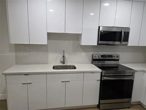 a kitchen with stainless steel appliances a stove microwave and sink