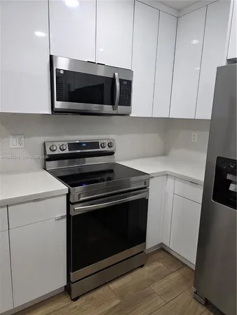 a view of a refrigerator in kitchen and an empty room