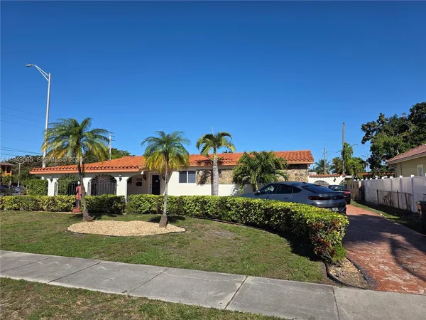 a view of a house with a yard and table and chairs under an umbrella
