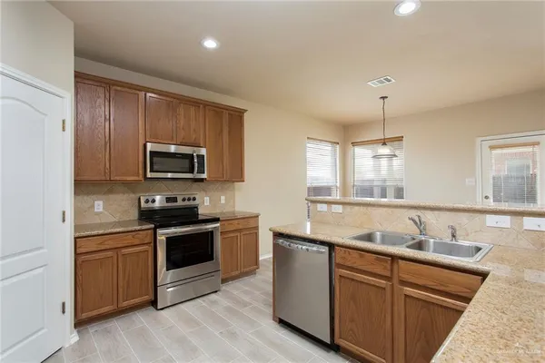 a kitchen with stainless steel appliances granite countertop a sink and stove top oven