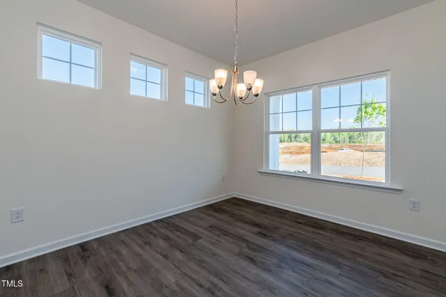 an empty room with wooden floor chandelier and windows