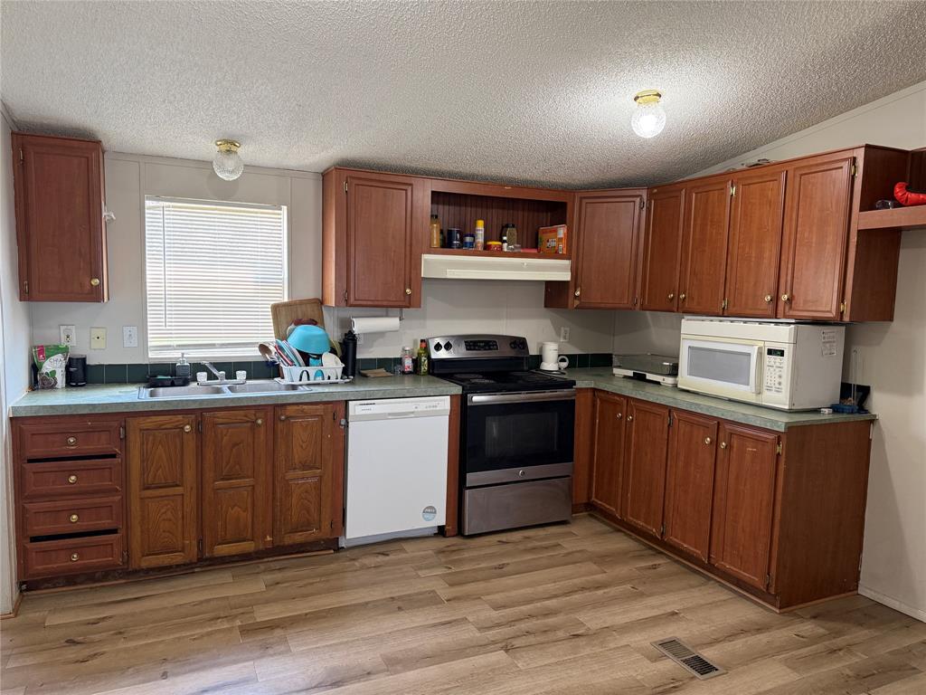 167 Blue Sky Lane Springtown, TX 76082 - Photo 13 of 34 a kitchen with stainless steel appliances granite countertop a stove a sink and a refrigerator