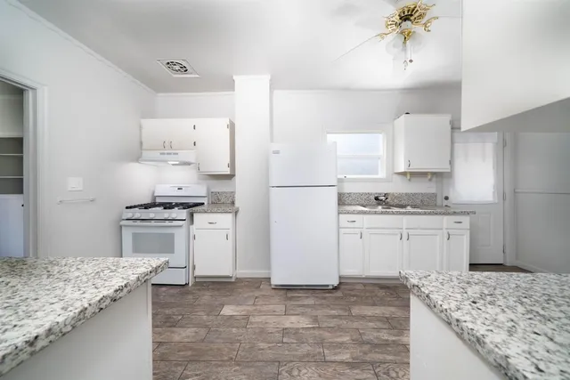 a kitchen with granite countertop a sink stove and refrigerator
