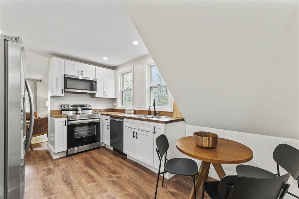 1142 Washington Street Whitman, MA 02382 - Photo 5 of 32 a kitchen with stainless steel appliances granite countertop a stove a sink a microwave a dining table and chairs