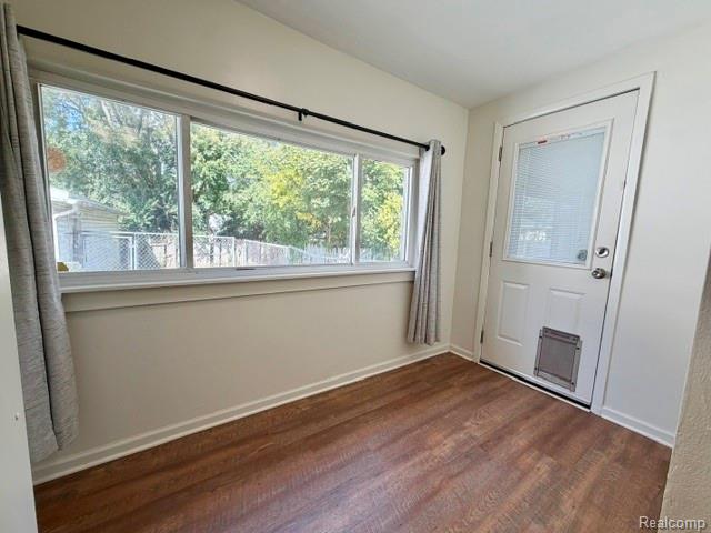2840 Miller Road Flint, MI 48503 - Photo 15 of 49 Wood-finish flooring, white trim, exterior door with integrated blinds, and a large window with a black curtain rod