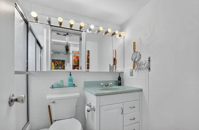 a bathroom with a granite countertop sink mirror vanity and toilet