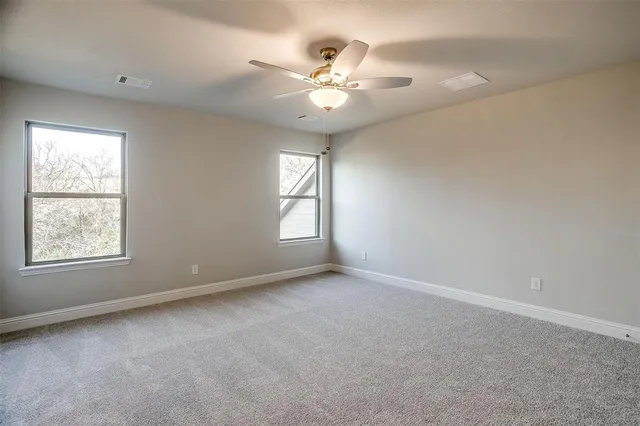 an empty room with windows and chandelier fan
