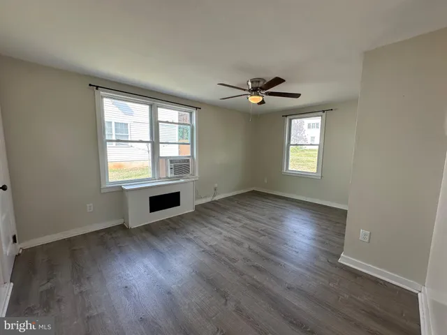 a view of an empty room with a window and wooden floor