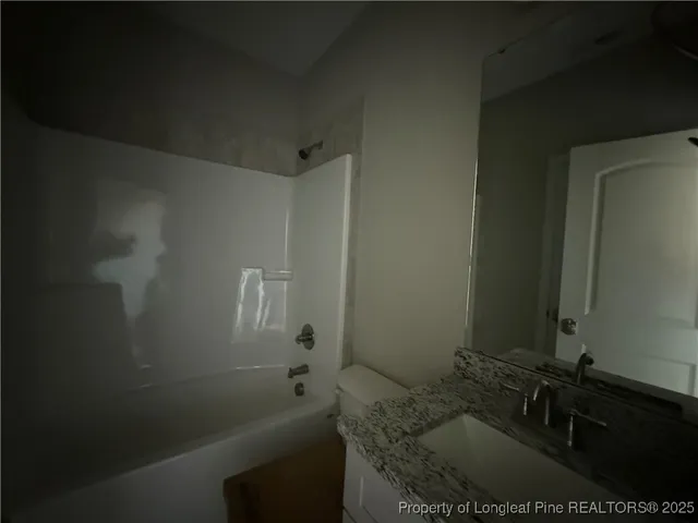 a bathroom with a granite countertop sink a toilet and shower