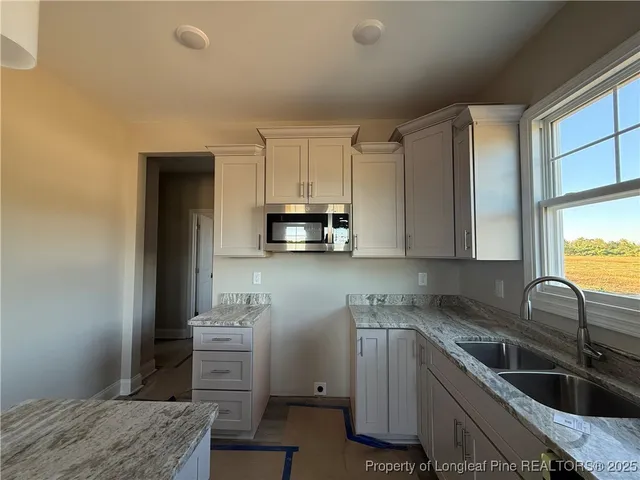 a kitchen with granite countertop a sink stove and cabinets