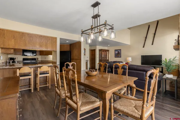 a view of a dining room with furniture a kitchen and chandelier