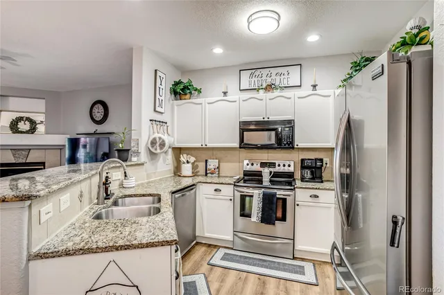 a kitchen with granite countertop a refrigerator stove and sink