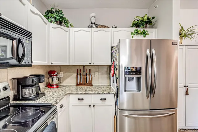 a kitchen with stainless steel appliances a refrigerator sink and white cabinets