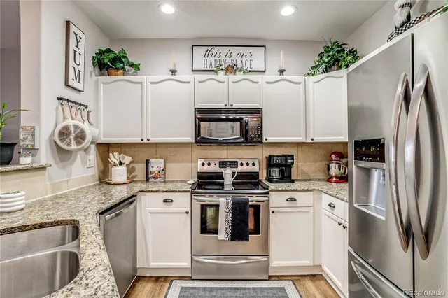 a kitchen with stainless steel appliances granite countertop a refrigerator sink and stove