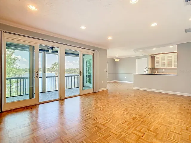 a view of an empty room with a window and wooden floor