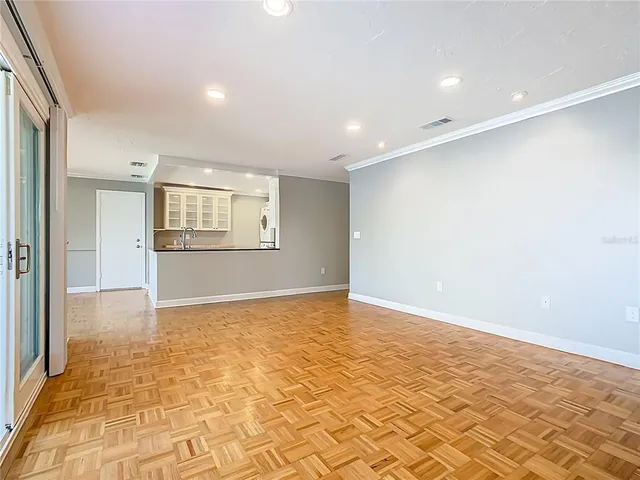 a view of an empty room with window and wooden floor
