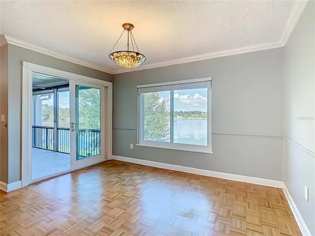 an empty room with wooden floor chandelier and windows