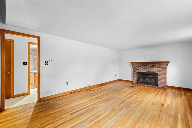 a view of empty room with wooden floor and fireplace