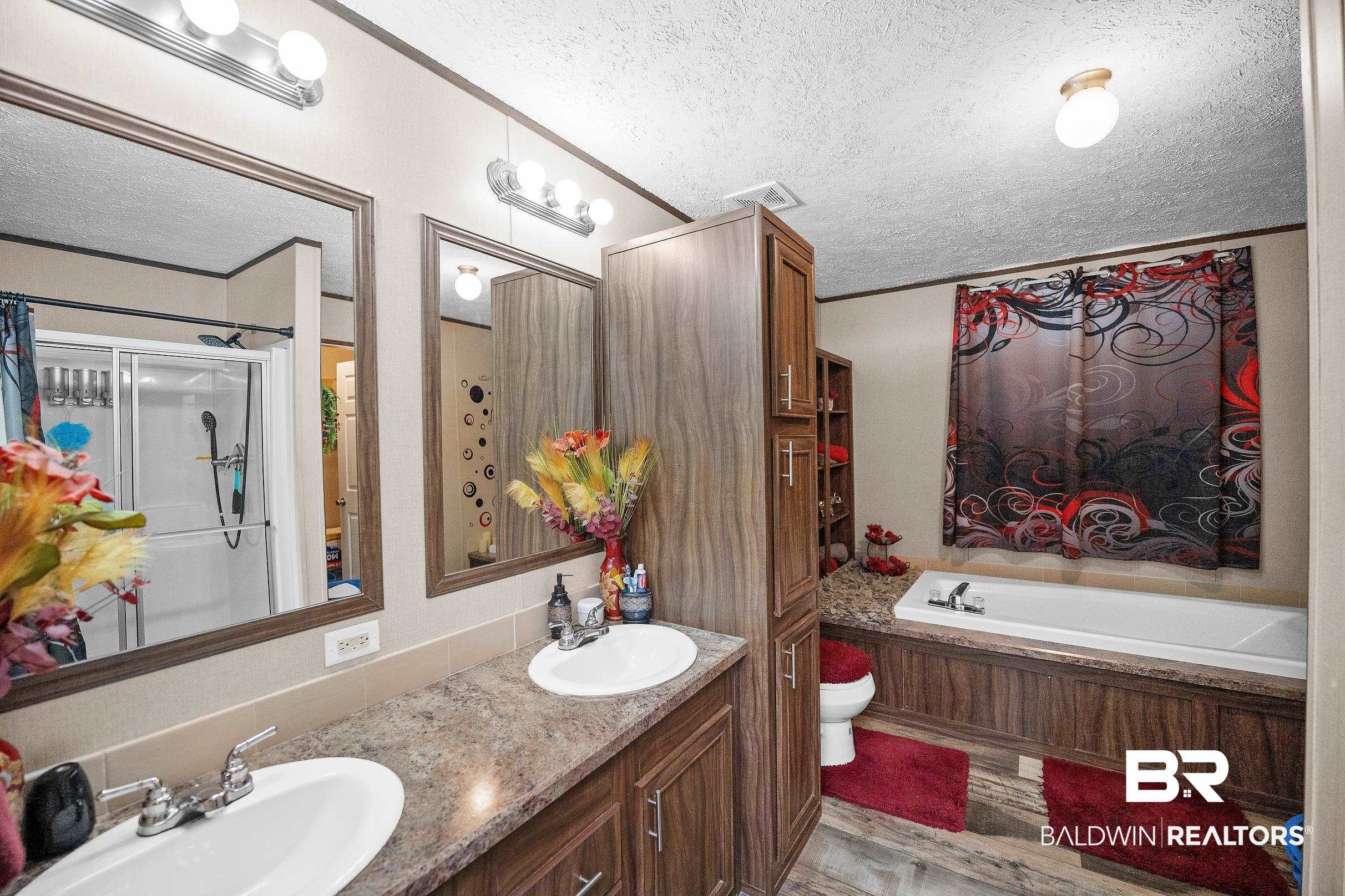 8630 Allison Lane Wilmer, AL 36587 - Photo 16 of 31 Bathroom with a textured ceiling, double vanity, a garden tub, light wood-style flooring, and a shower