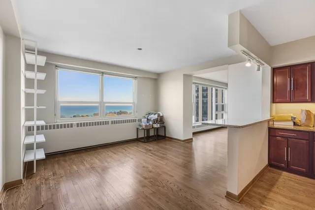 a view of an empty room with window and wooden floor