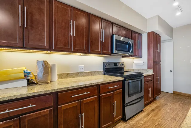 a kitchen with granite countertop stainless steel appliances wooden cabinets a stove top oven and granite counter tops