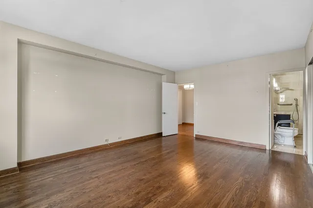 a view of an empty room with wooden floor and closet