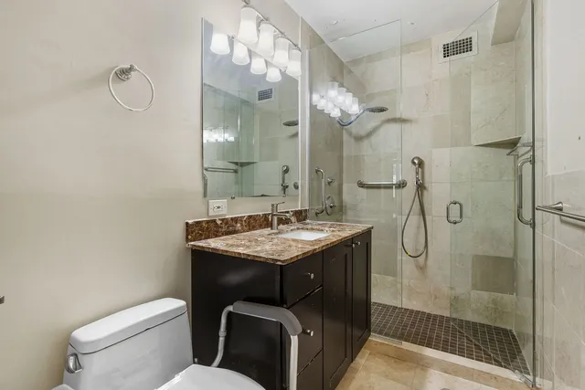 a bathroom with a granite countertop sink a toilet and shower